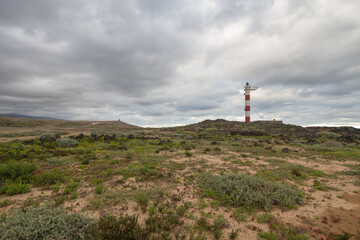 Fototapeta na wymiar Desert landscape with volcanic rocks, lighthouse and storm clouds. Aabdes, Tenerife, Canary Islands. Spain