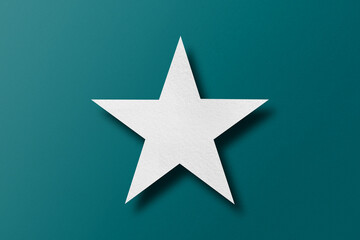 paper cut star shape with light and shadow placed on a green paper background