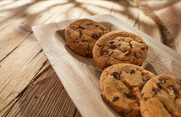 chocolate chip cookies on a wooden tray closeup. breadboard on an old wooden table with cracks and...