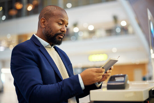 Black man, reading passport and airport for travel, security and identity for global transportation service. African businessman, documents and concierge for immigration with international transport - Powered by Adobe