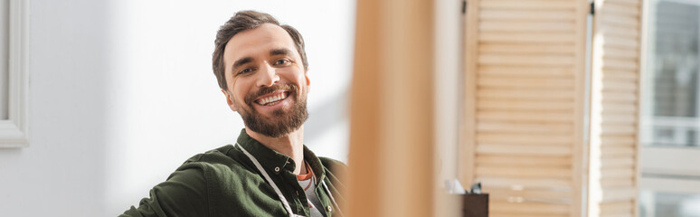 Positive carpenter looking at camera in workshop, banner.