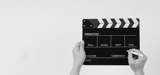 The hand is holding a black clapper board and marker Pen on white background.