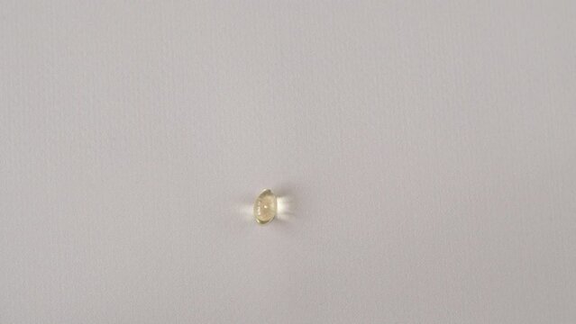 A vitamin d3 capsule in a woman's hand in close-up. Fish oil pill or vitamin D supplement.