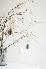 Tablescaping with Easter paper eggs hanging on branches.