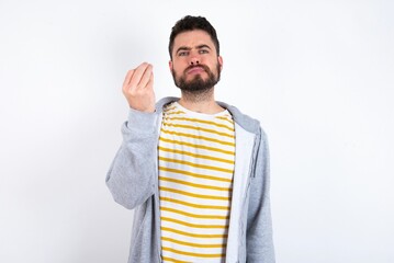 caucasian man wearing casual sportswear over white wall angry gesturing typical italian gesture...
