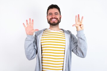 caucasian man wearing casual sportswear over white wall showing and pointing up with fingers number...