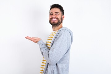caucasian man wearing casual sportswear over white wall pointing aside with hands open palms showing copy space, presenting advertisement smiling excited happy