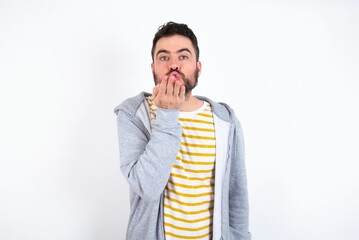 caucasian man wearing casual sportswear over white wall looking at the camera blowing a kiss with hand on air being lovely and sexy. Love expression.