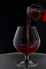 Pouring wine into a glass on a dark background