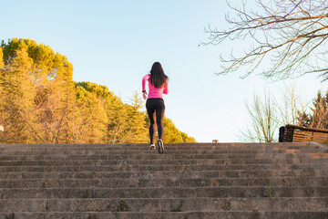 Female runner in sportswear exercising in a park at sunset