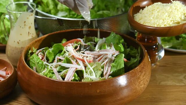 woman chef mix fresh baby cos salad and pour salad dressing in glass blow. Organic Vegetables mix all green salad In glass bowl. Breakfast fresh salad and clean vegetable.