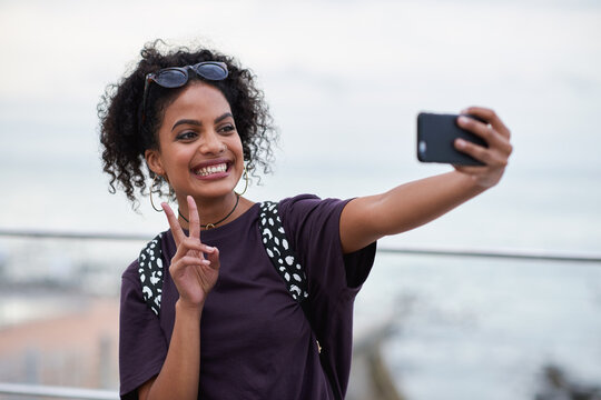 Selfie, peace sign and smile of black woman in city taking pictures for happy memory. Travel, street and female with v hand gesture, having fun and enjoying time while taking photo for social media.