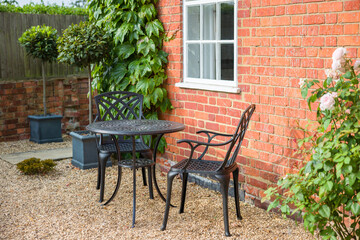 Fototapeta na wymiar Garden furniture on gravel patio area, UK garden