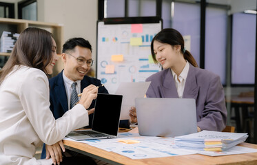 Asian business corporate team brainstorming, planning strategy having a discussion Analysis investment researching with chart at office desk documents in office.