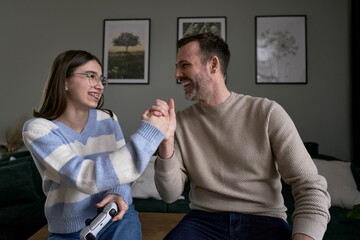 Caucasian teenager girl with dad playing at video game