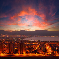Sunrise panoramic view of Eilat. Israel.  Glowing town lights at night. Red Sea. Lights of Aqaba, Jordan city on the opposite side of the bay (gulf). Jordan mountains in the in the foggy distance