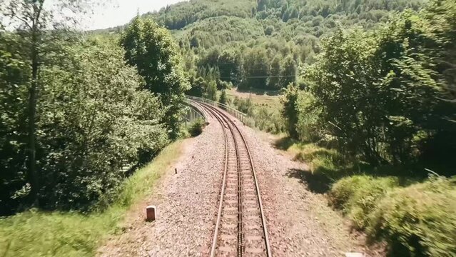 Aerial view filmed with FPV racing drone. Flying through a small gap in between spruce trees. Descending very close above a railway track on an old railway bridge and a winding road. LuPa Creative.