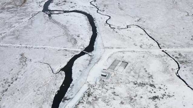 Tilting drone shot of the snowy Gress river with Gress beach and Point in the background on the Outer Hebrides of Scotland.