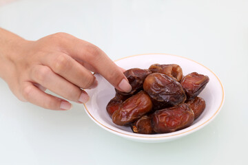 Close up photo of woman's hand taking a date palm fruit on the table. Ramadan concept