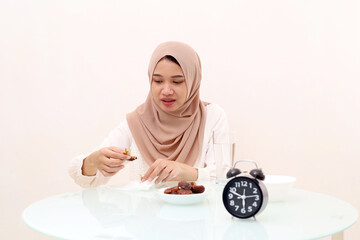 Young asian muslim woman picking date palm fruit for breaking her fasting. Ramadhan concept