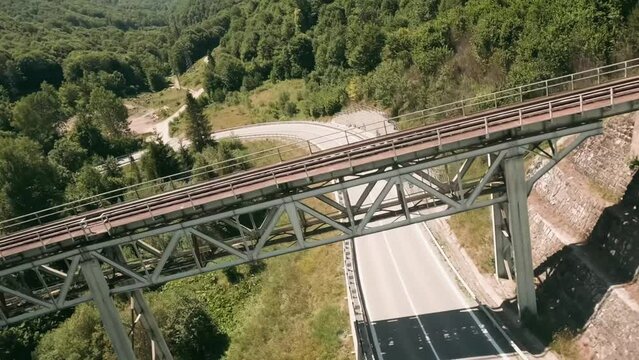 Flying fast with FPV drone on serpentine with an old railway bridge passing by a white long truck with a fuel tank and a car  driving in oposite direction. LuPa Creative.