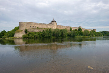 Naklejka na ściany i meble View of the ancient Ivangorod fortress from the side of the Narva river on a cloudy August morning. Border of Estonia and Russia