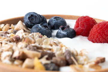 Yogurt with berries and muesli for breakfast in bowl isolated on white background. Close up