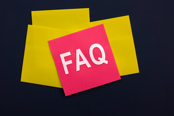 FAQ - Frequently Asked Questions - inscription of a pink square sticky note paper on dark background. Top view. Instructions and rules on Internet sites