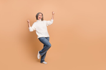 Fototapeta na wymiar Full body length photo of overjoyed funny pensioner woman fists up celebrating victory project finance manager isolated on beige color background