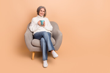 Fototapeta na wymiar Full length photo of pretty dreamy lady dressed white sweater enjoying hot beverage empty space isolated beige color background