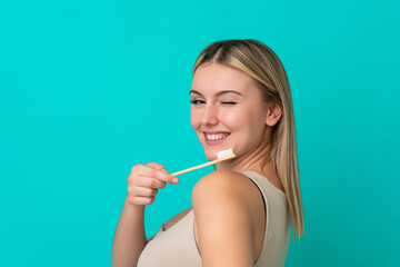 Young caucasian woman isolated on blue background with a toothbrush and happy expression