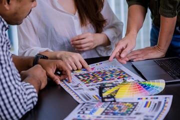 Crop image of worker checking print quality of media graphics proof print and color tone in printing industry. Selected focus