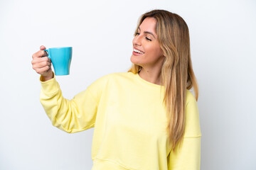 Young Uruguayan woman holding cup of coffee isolated on white background with happy expression