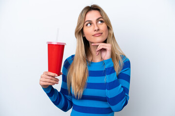 Young Uruguayan woman drinking soda isolated on white background having doubts while looking up