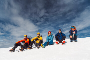 Group of five mountaineers sitting on the sun, high up in the snowy Alps