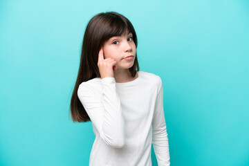 Little caucasian girl isolated on blue background thinking an idea