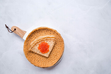 Russian traditions. Broad Maslenitsa. A stack of pancakes, sour cream and red caviar on a light background. Close-up.