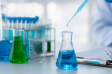Lab assistant, a medical scientist, a chemistry researcher holds a glass tube through the blood sample, does a chemical experiment and examines a patient's blood sample. Medicine and research concept.