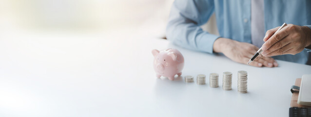 Fototapeta premium Person with pile of coins and piggy bank, money saving concept for future use and financial stability, salary management, personal finance, investment savings.