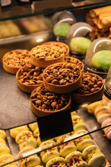 Tartlets with peanuts and caramel in the window of a coffee shop under the light. A sweet, nutty, delicious dessert. Baking with nuts