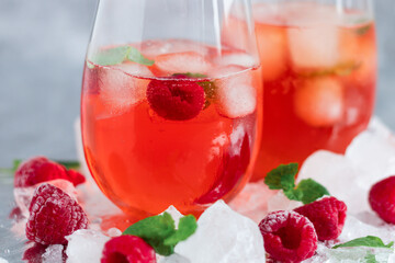 Cool cocktail with ice and mint and raspberry. On a gray background. Summer.