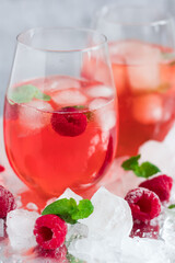 Cool cocktail with ice and mint and raspberry. On a gray background. Summer.
