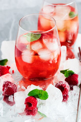 Cool cocktail with ice and mint and raspberry. On a gray background. Summer.