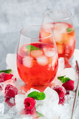 Cool cocktail with ice and mint and raspberry. On a gray background. Summer.