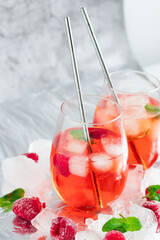 Cool cocktail with ice and mint and raspberry. On a gray background. Summer.