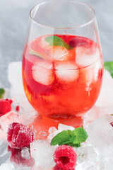 Cool cocktail with ice and mint and raspberry. On a gray background. Summer.