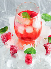 Cool cocktail with ice and mint and raspberry. On a gray background. Summer.