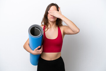 Young sport caucasian woman going to yoga classes while holding a mat isolated on white background covering eyes by hands. Do not want to see something