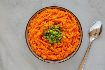 Homemade Creamy Mashed Sweet Potatoes with MIlk and Butter in a Bowl on a gray background, top view.