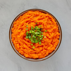Homemade Creamy Mashed Sweet Potatoes with MIlk and Butter in a Bowl on a gray background, top view.